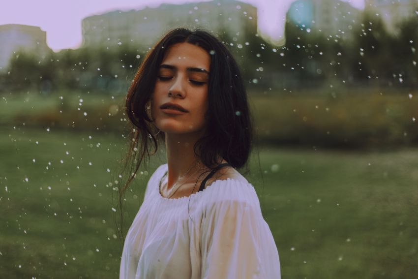 femme dehors sous la pluie avec les yeux fermés