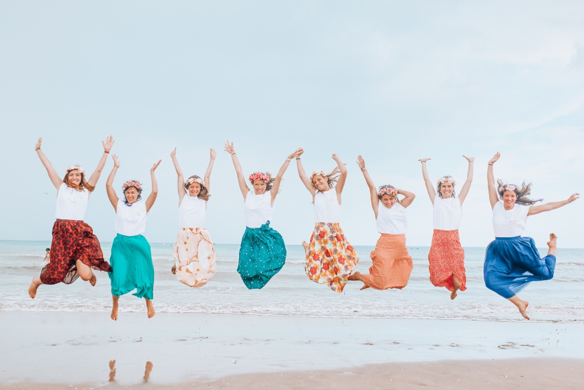 groupe de copines en jupes fleuries qui sautent sur la plage