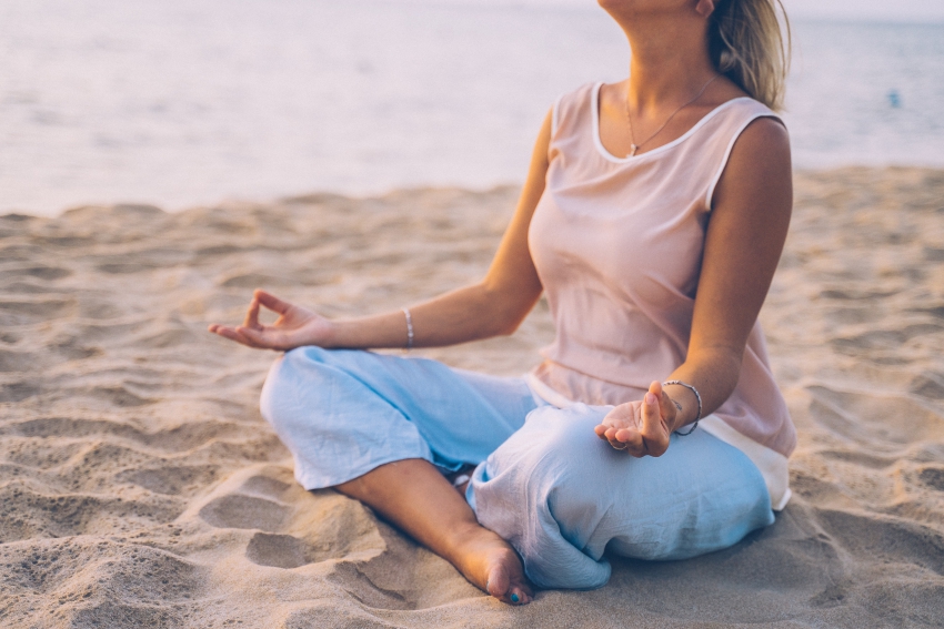 femme qui medite sur le sable au bord de leau